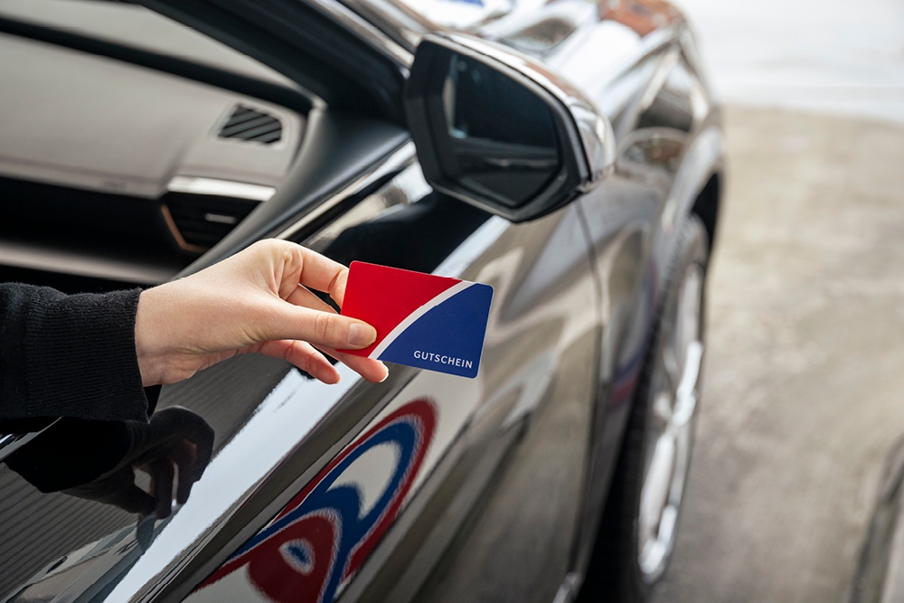 Q1 Gutschein als Mitarbeiter-Benefit Q1 Gutschein wird aus dem Auto gehalten